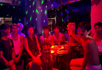 People at POC Bar, a gay bar in Phnom Penh. Nightlife scene with men in a dimly lit space, enjoying drinks and socializing. Gay travel Cambodia.