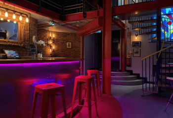 Interior of The Boilerhouse gay sauna in Dublin. Bar with red stools, stairs, and spiral staircase. Gay travel advice.